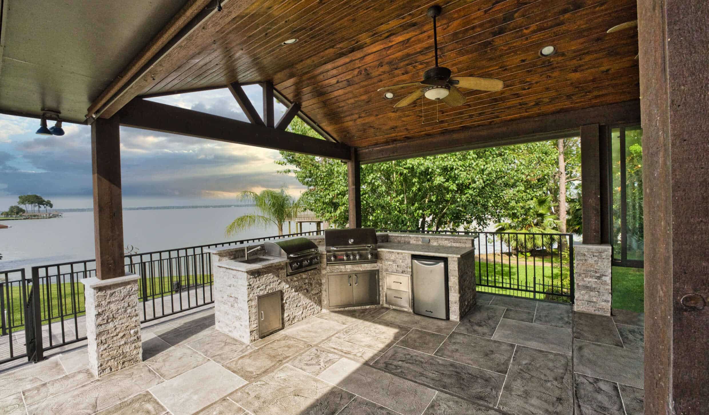 An outdoor kitchen and covered patio with a gorgeous lake view